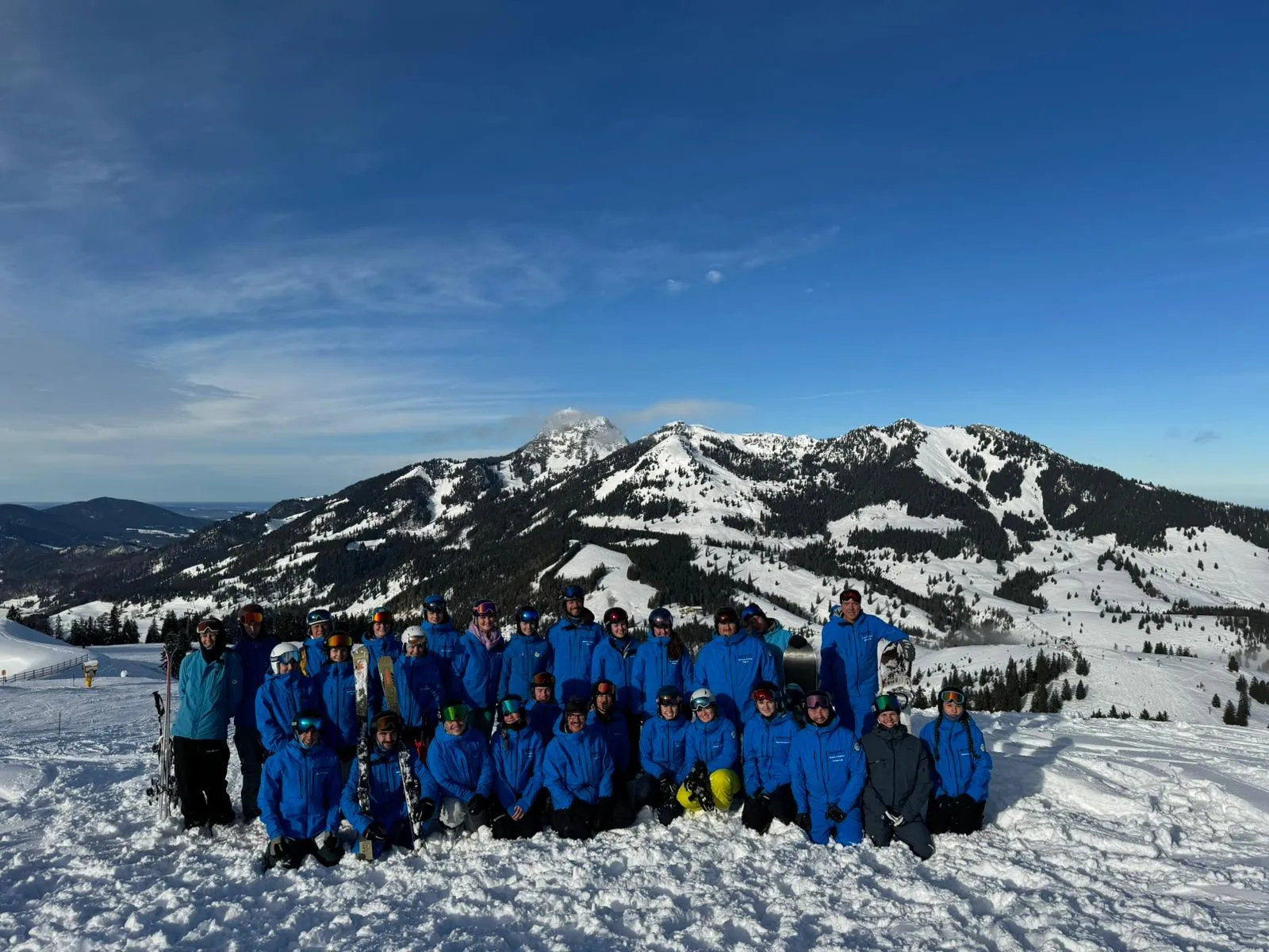 Das Team der Skischule Sudelfeld in blauen Jacken vor dem Sudelfeld-Panorama