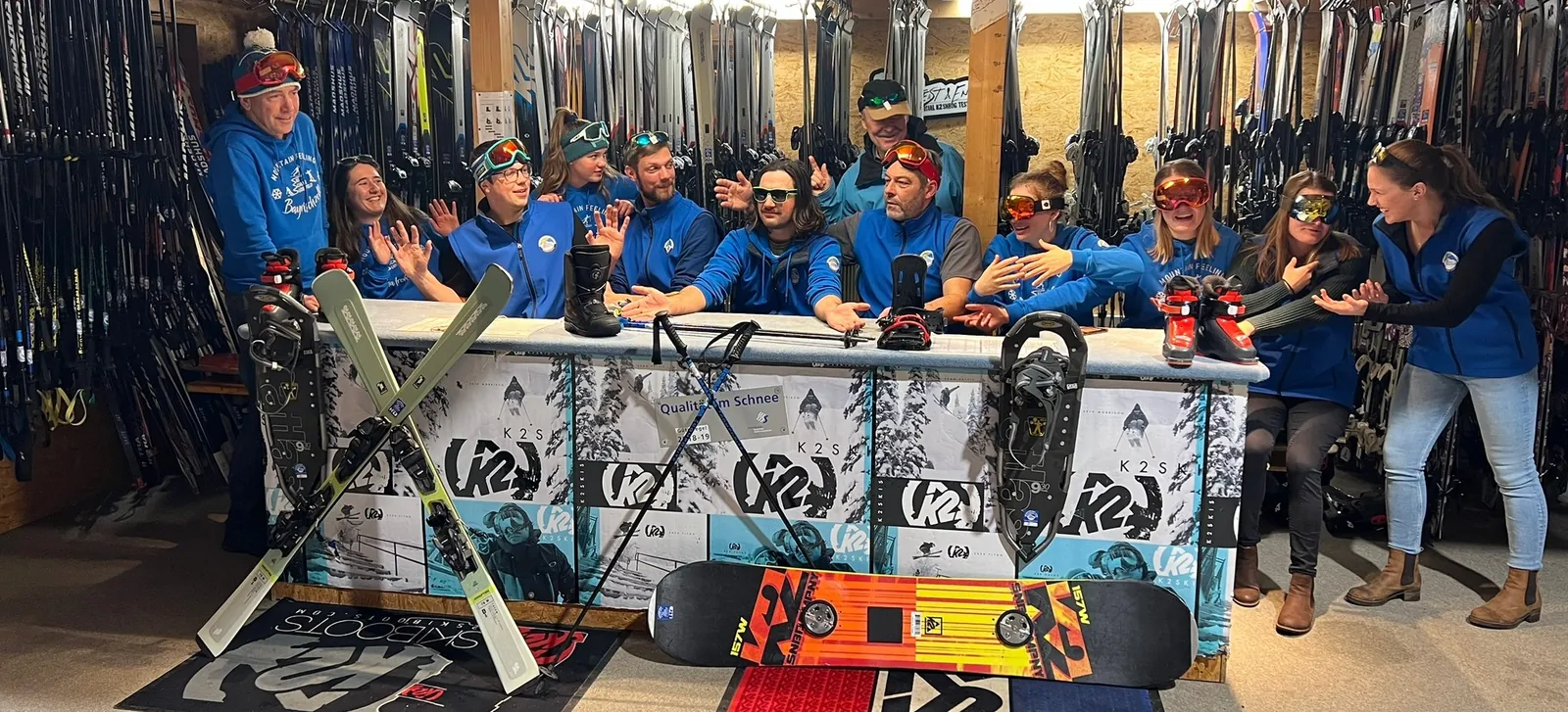 Das Verleihteam der Skischule Sudelfeld an der Theke mit Ski, Snowboards und Schneeschuhen